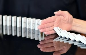 The hand stops the chain of falling dominoes (1)