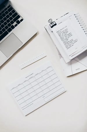 The laptop is on the table next to the notebook and planner