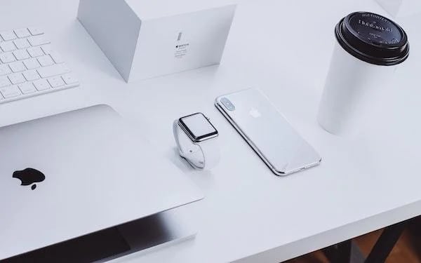 Apple products lying on the desk with cup of coffee