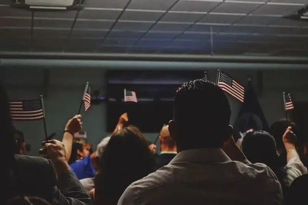 People stand and wave small American flags in a semi-dark room