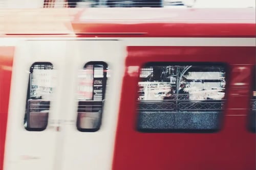 Біло-червоний поїзд швидко проїжджає повз