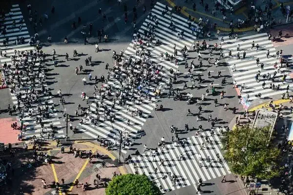 A large intersection with several pedestrian crossings in a large number of people 