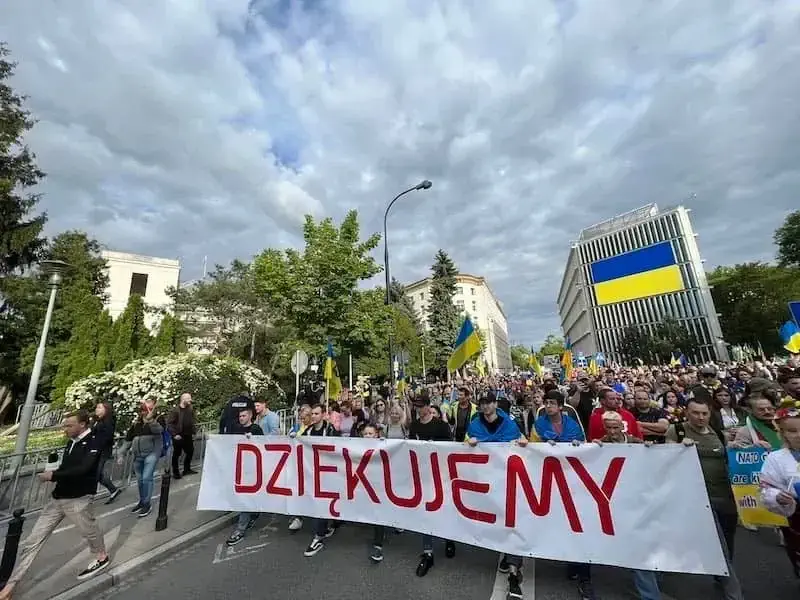 People marching with a banner and Ukrainian flags